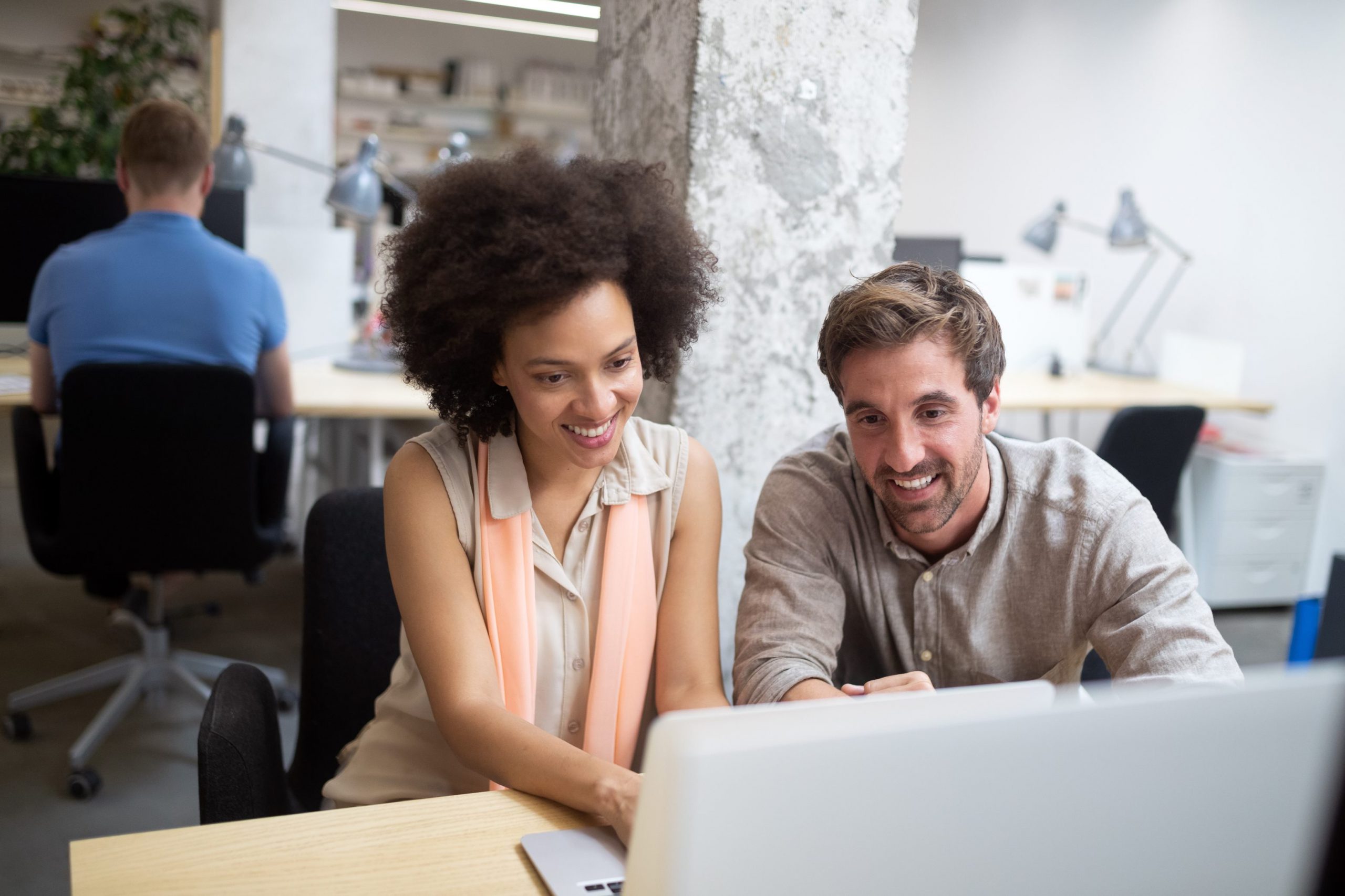 two people looking at a laptop in an office